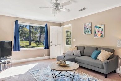Carpeted living area with ornamental molding and ceiling fan