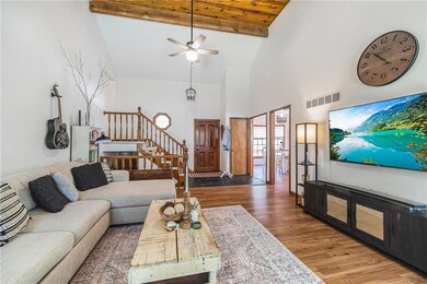 Living area with wood finished floors, high vaulted ceiling, stairs, ceiling fan, and a wood ceiling with exposed beams