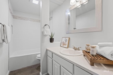 Full bathroom with wood finished floors, vanity, and bathing tub / shower combination