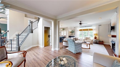 Living area featuring wood finished floors, crown molding, a fireplace, baseboards, and stairs
