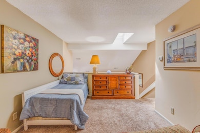 Carpeted bedroom featuring a textured ceiling, bas