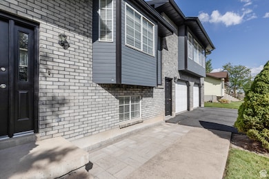 View of property exterior featuring brick siding, asphalt driveway, and an attached garage