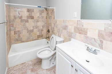 Full bathroom featuring tile walls, vanity, toilet