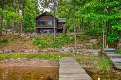 Standing back partway on the dock, looking past the sandy beach to the cabin