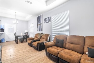 Living area featuring a chandelier, a raised ceiling, and light wood-style flooring