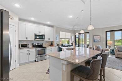 Kitchen with appliances with stainless steel finishes, white cabinets, decorative light fixtures, open floor plan, and light tile patterned floors