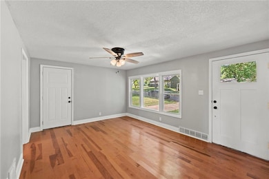 Entryway with light wood finished floors, ceiling fan, and a textured ceiling
