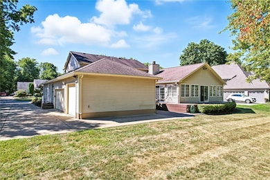 Back of house featuring driveway, a lawn, and an attached garage
