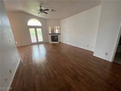 Unfurnished living room featuring dark wood finished floors, a tile fireplace, lofted ceiling, ceiling fan, and french doors