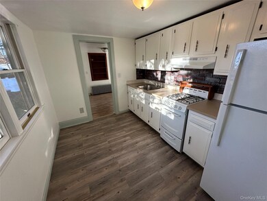Kitchen with white appliances, light countertops, white cabinetry, and dark wood-style floors