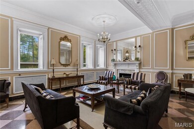 Living room with a decorative wall, a fireplace, ornamental molding, and a chandelier