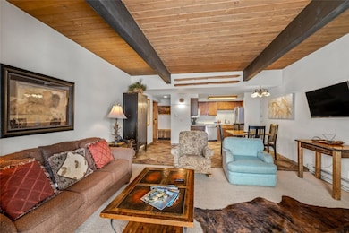 Living room with light colored carpet and a wood ceiling with exposed beams