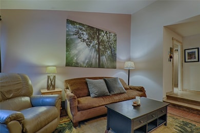 Living room with wood finished floors, vaulted cei