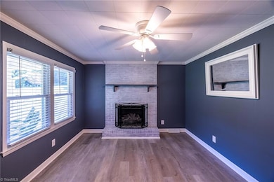 Living Room: Features include new LVP flooring for easy cleaning, the 2 windows for natural lighting with blinds for privacy, a ceiling fan with light, fresh new paint, decorative crown molding, the decorative mirror and the fireplace with gas logs for some additional heat on those cool days.