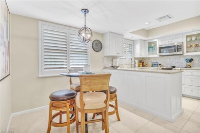 Kitchen featuring white cabinets, visible vents, stainless steel microwave, glass insert cabinets, and backsplash