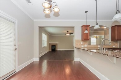 Kitchen with a chandelier, brown cabinetry, a ceiling fan, light stone countertops, and ornamental molding