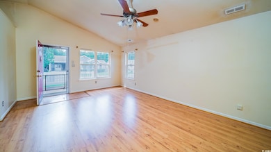 Empty room featuring wood finished floors, baseboards, ceiling fan, and high vaulted ceiling