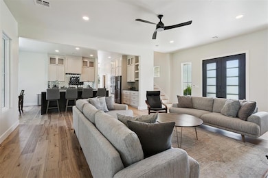 Living room with ceiling fan, recessed lighting, light wood-style flooring, stairs, and french doors