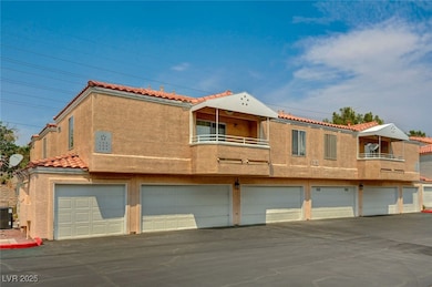 View of front facade featuring a balcony, stucco siding, a tiled roof, and an attached garage