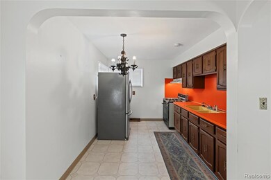 Kitchen with arched walkways, dark brown cabinetry, freestanding refrigerator, and gas stove