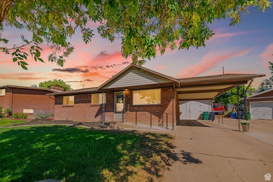 Ranch-style house featuring an outbuilding, an attached carport, a lawn, brick siding, and a garage