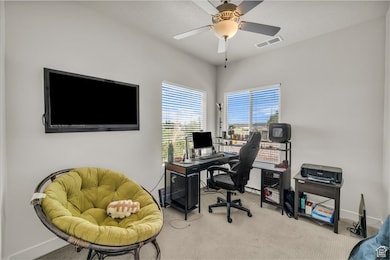 Carpeted office space featuring baseboards and a ceiling fan