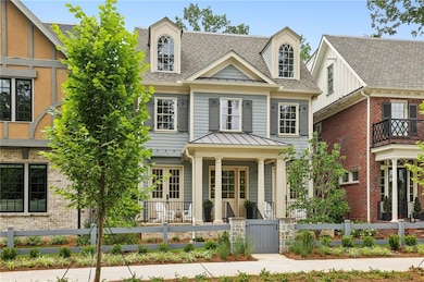 View of front of house featuring a porch, a standing seam roof, roof with shingles, a fenced front yard, and metal roof