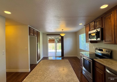 Kitchen featuring appliances with stainless steel finishes, recessed lighting, a textured ceiling, dark wood-style floors, and hanging light fixtures