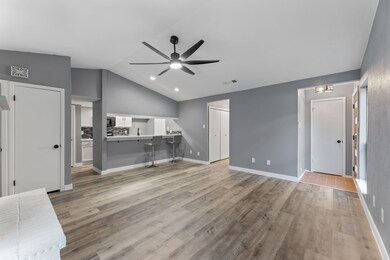 Unfurnished living room featuring ceiling fan, vau