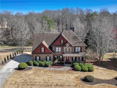 View of front of home featuring a porch, a view of trees, a chimney, concrete driveway, and a front lawn