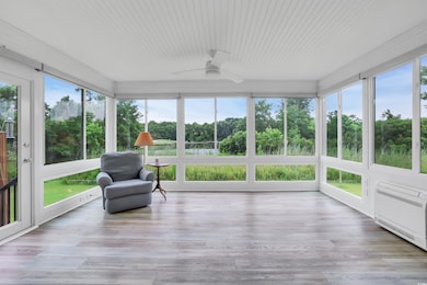 Sunroom with a wooden deck, view of wooded area, and wood finished floors