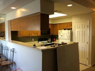 Kitchen with brown cabinets, white appliances, light tile patterned floors, light countertops, and a peninsula