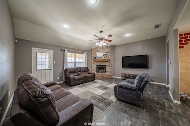 Living room featuring vaulted ceiling, a textured ceiling, dark wood-type flooring, a brick fireplace, and a ceiling fan