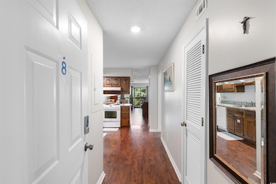 Hallway with a sink, dark wood-style floors, and baseboards