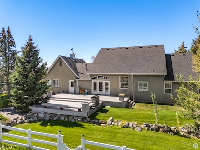 Rear view of property with a lawn, a shingled roof, stucco siding, and a wooden deck