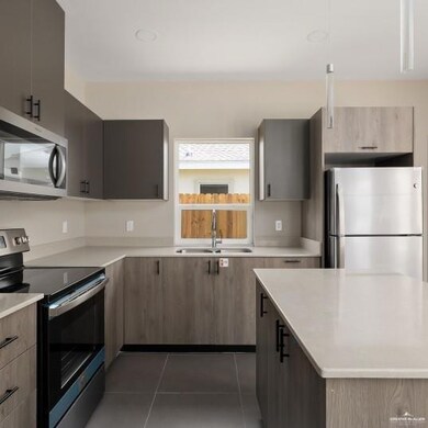 Kitchen with stainless steel appliances, dark tile patterned flooring, and modern cabinets