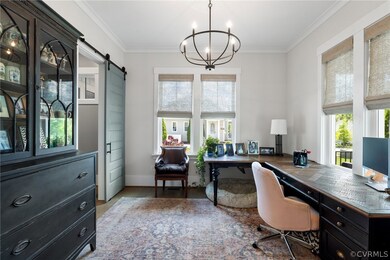 Office space with a barn door, ornamental molding, an inviting chandelier, and wood-type flooring