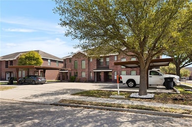 View of property with covered and uncovered parking and brick siding