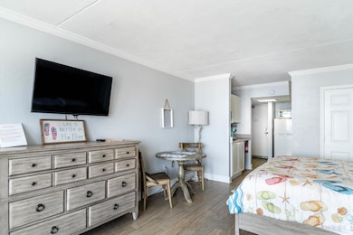 Bedroom featuring crown molding, white fridge, and