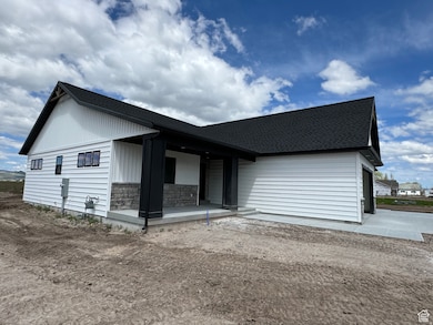 Rear view of house featuring a shingled roof, stone siding, and a patio area