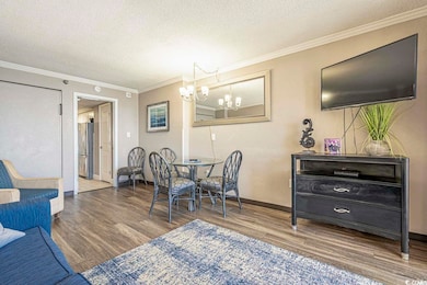Dining space with baseboards, ornamental molding, wood finished floors, a textured ceiling, and a chandelier