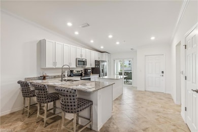 Kitchen featuring a kitchen breakfast bar, kitchen peninsula, stainless steel appliances, sink, and white cabinetry
