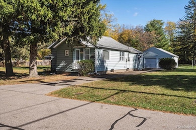View of front facade featuring a front lawn, an outdoor structure, and roof with shingles
