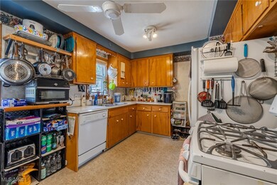 Kitchen featuring brown cabinets, white appliances, light countertops, light floors, and ceiling fan