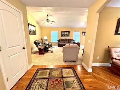 Living room with arched walkways, light wood-style flooring, lofted ceiling, ceiling fan, and a textured ceiling