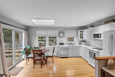 Kitchen featuring decorative backsplash, light countertops, white appliances, and a sink