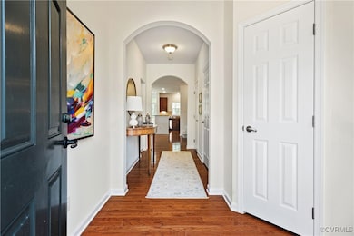 Corridor with arched walkways, baseboards, and dar
