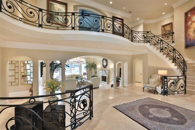 This opposing view of the foyer displays the wrought iron railing that frames the circular Travertine stairs that lead to three bedrooms on the second floor. A second primary bedroom suite is located through the hallway under the stairs.
