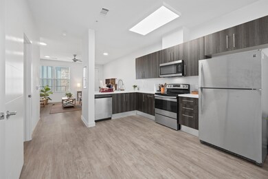 Kitchen with appliances with stainless steel finishes, modern cabinets, light wood-style flooring, dark brown cabinets, and backsplash