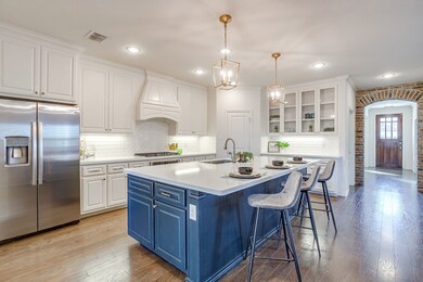 Kitchen with white cabinetry, stainless steel fridge, decorative backsplash, arched walkways, and recessed lighting